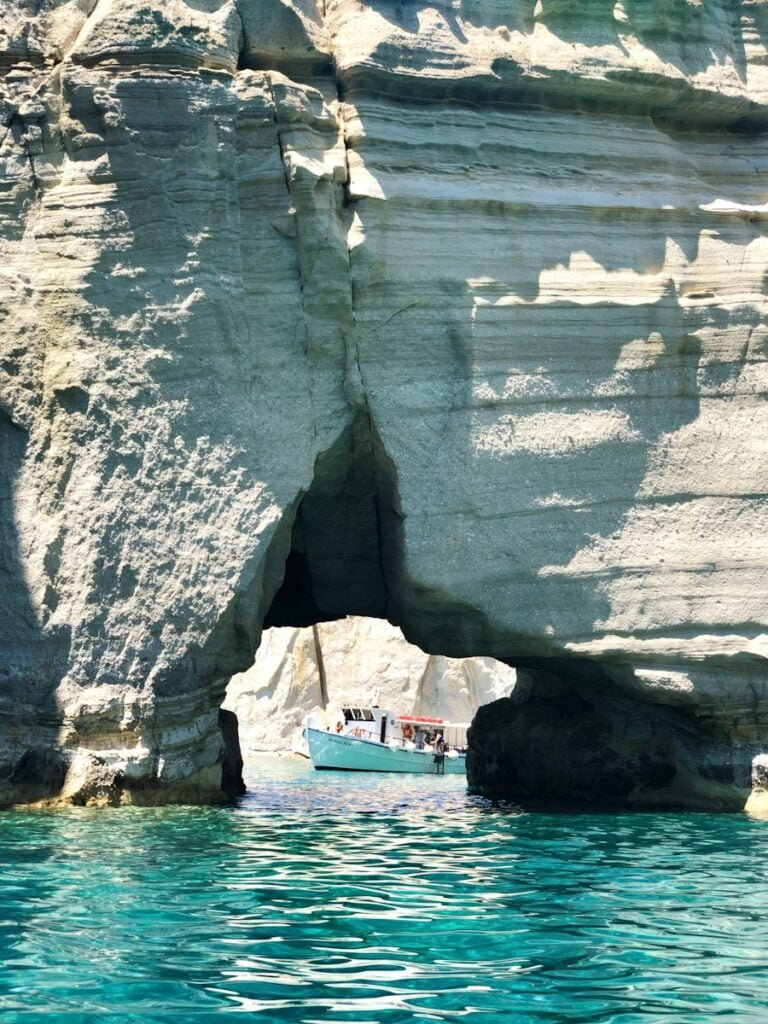 white boat on sea near rock formation during daytime